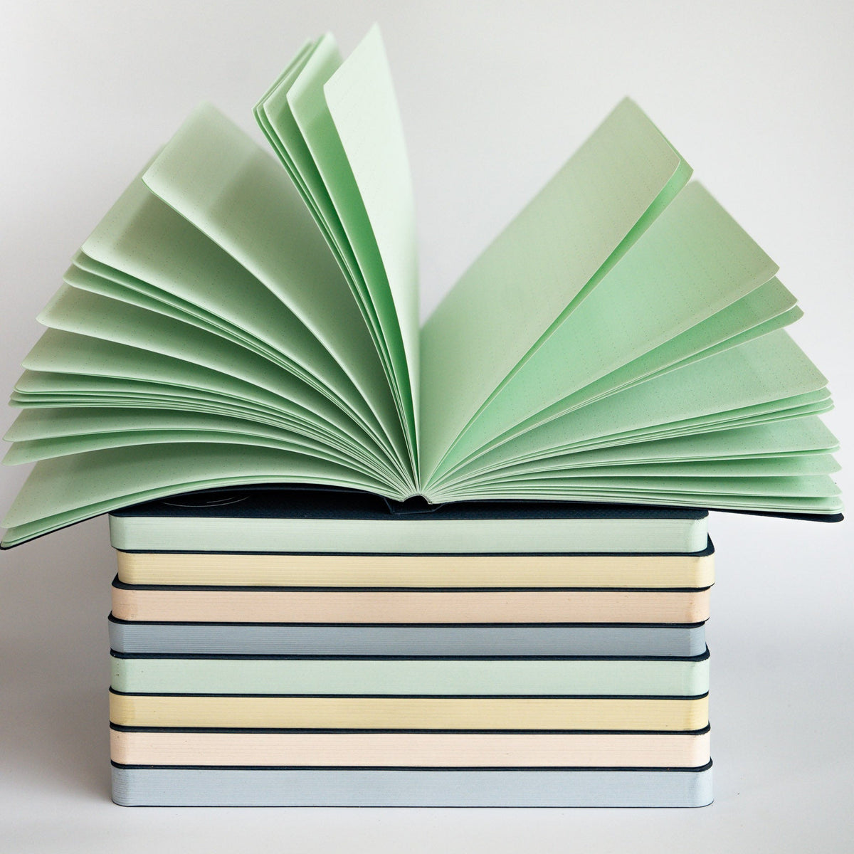 Stack of books with open pages in pastel colors on a light background