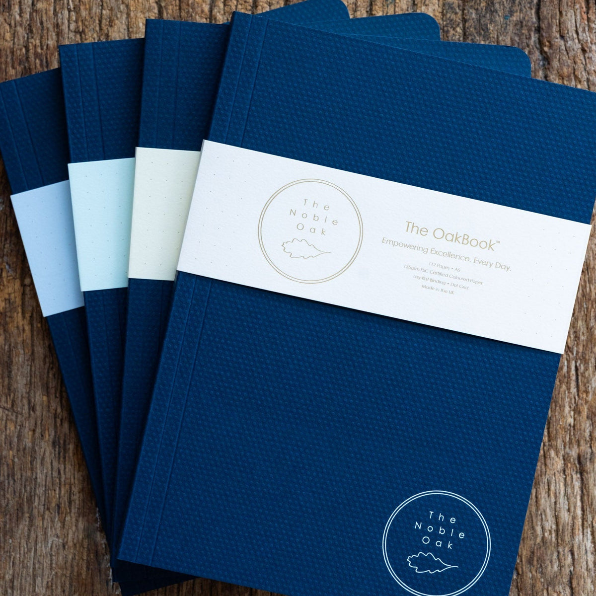 Set of blue notebooks with a brand label on a wooden surface